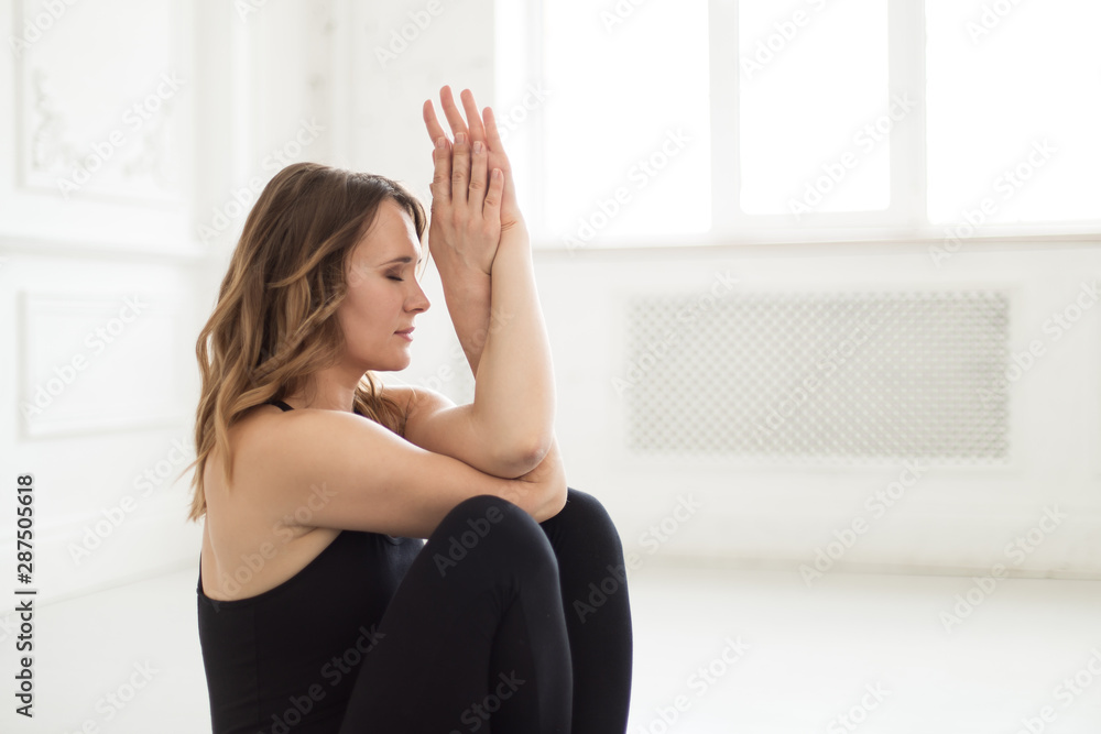 Woman in a tracksuit sits against the wall holding her hands in front of her face Woman in a tracksuit sits against the wall holding her hands in front of her face