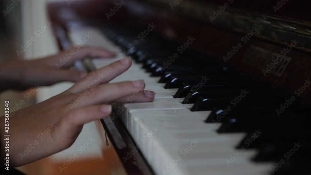 A child learns how to play a musical instrument. Hands of a little girl press the piano keys close-up. A child learns how to play a musical instrument. Hands of a little girl press the piano keys close-up.