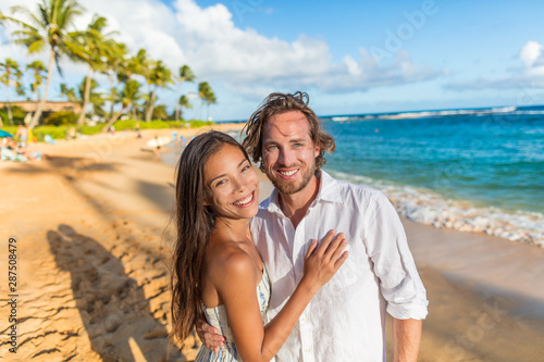 Happy couple on romantic sunset beach stroll walking on honeymoon Hawaii winter escape holiday. Smiilng Asian woman and Caucasian man, biracial couple. © Maridav