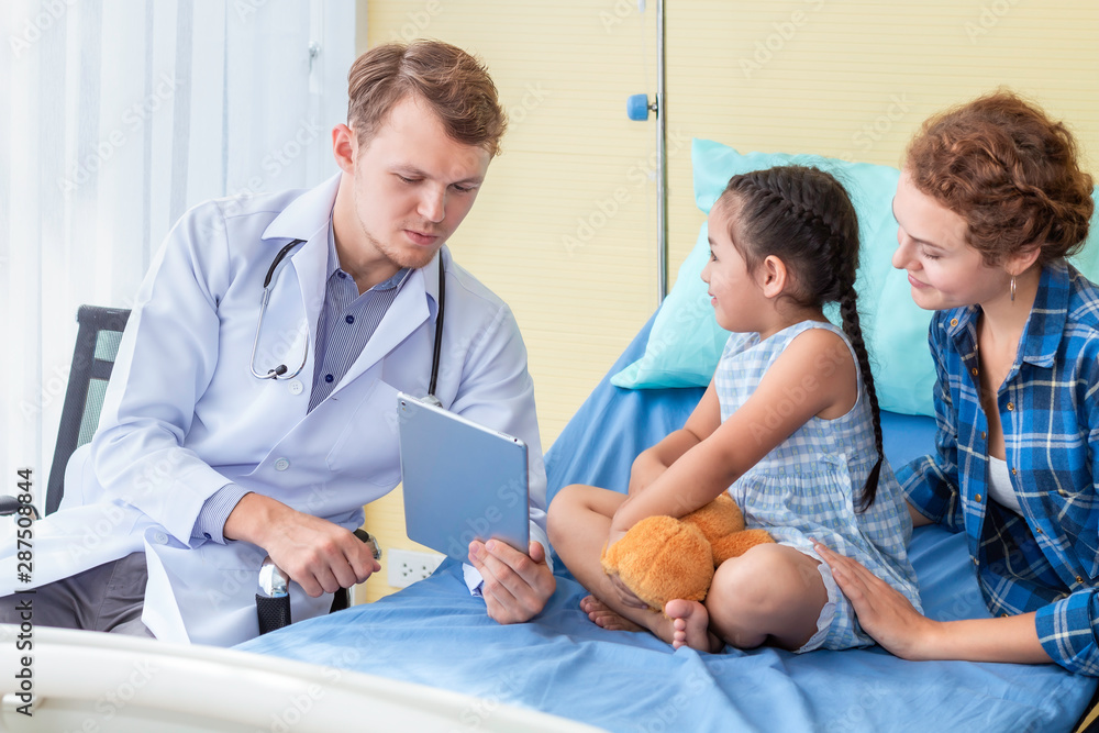 Pediatrician (doctor) man recording and taking information to tablet with little girl patient and mother in hospital. Pediatrician (doctor) man recording and taking information to tablet with little girl patient and mother in hospital.