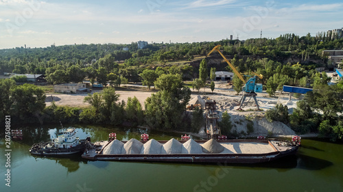 Fényképezés Crane is loading sand and gravel onto barge ship for river transport