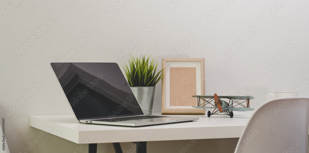 Modern comfortable office with open blank screen laptop computer with mock up frame Modern comfortable office with open blank screen laptop computer with mock up frame