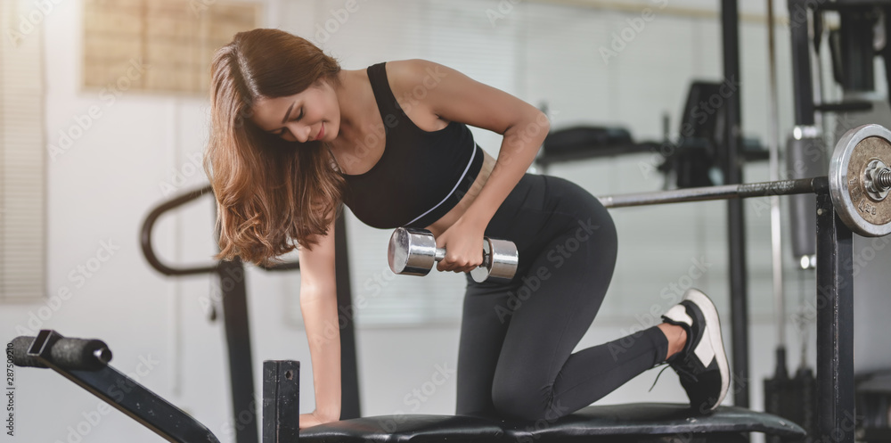 Fit asian athletic woman lifting weights inside home gym Fit asian athletic woman lifting weights inside home gym