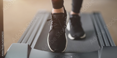 Close-up view of athletic woman running in jogging sneakers on treadmill