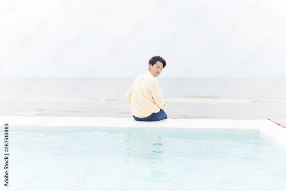 A young man sitting quietly at the pools edge overlooking the ocean A young man sitting quietly at the pools edge overlooking the ocean