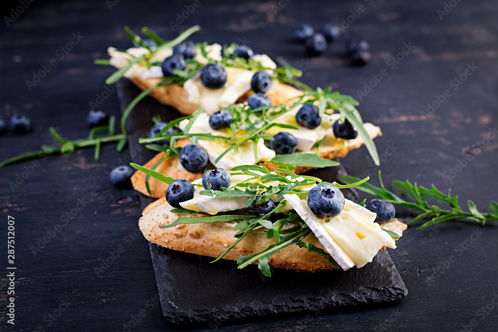 Plakat Bruschetta. Toast crostini with fresh berries blueberry and honey, brie cheese, arugula. Italian cuisine