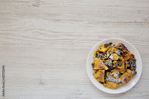 Homemade german Kaiserschmarrn pancake on a white plate on a white wooden background, overhead view. Flat lay, top view, from above. Copy space