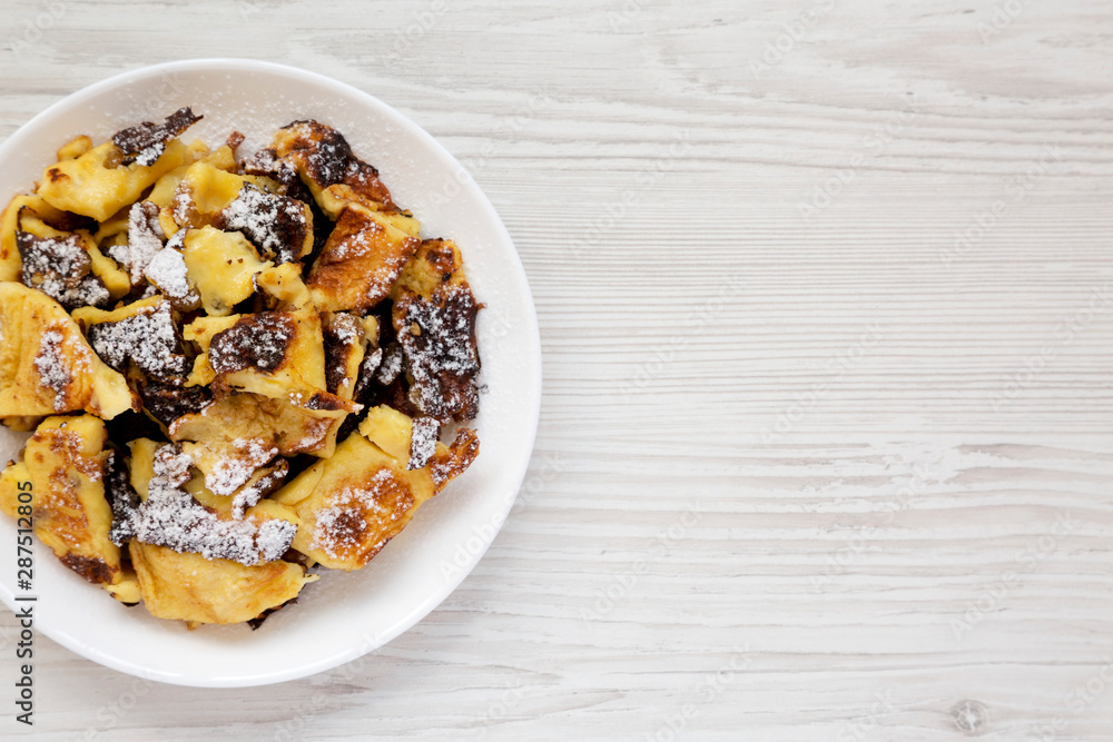 Homemade german Kaiserschmarrn pancake on a white wooden background, top view. Flat lay, overhead, from above. Space for text. Homemade german Kaiserschmarrn pancake on a white wooden background, top view. Flat lay, overhead, from above. Space for text.