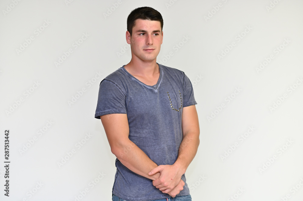 Portrait of a handsome young man with black hair in a blue and gray t-shirt on a white background. Shows emotions in various poses, talking. Portrait of a handsome young man with black hair in a blue and gray t-shirt on a white background. Shows emotions in various poses, talking.