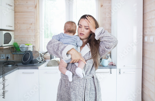 Young beautiful tired sterssed exhausted mother with baby girl child. Postnatal depression, motherhood difficulty idea concept. 