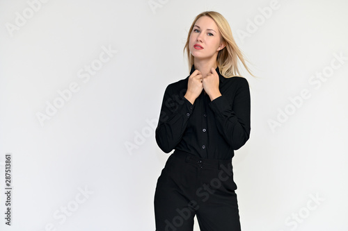 Portrait of a pretty blonde girl in a black suit on a white background. Beauty, brightness, happiness, business look. Shows different emotions in different poses.