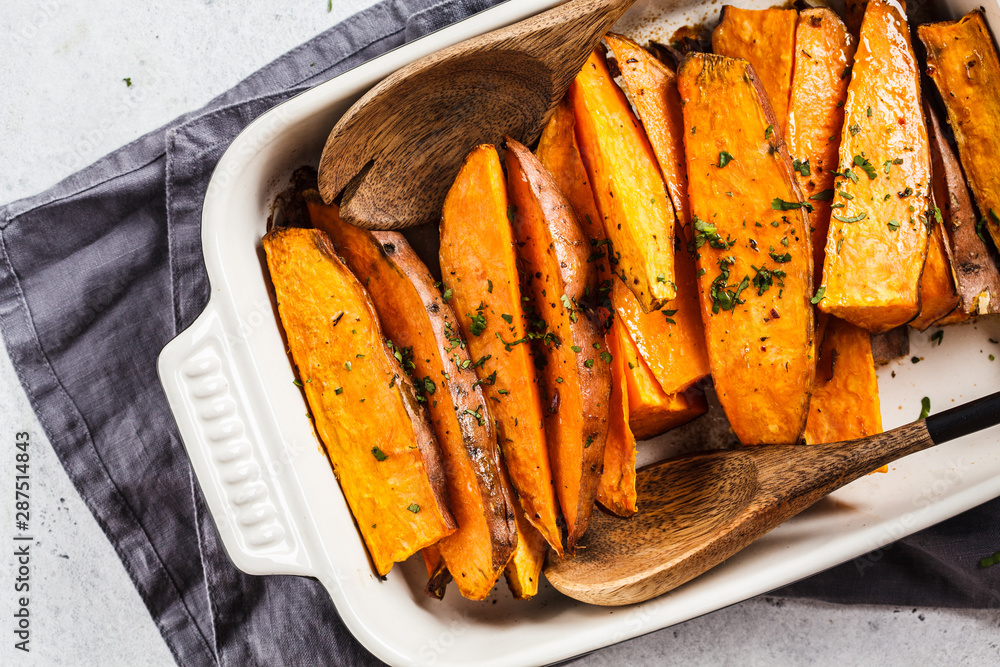 Baked sweet potato slices with spices in oven dish. Healthy vegan food concept. - obrazy, fototapety, plakaty 