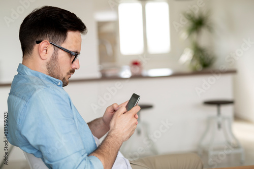 Happy man using mobile phone at home