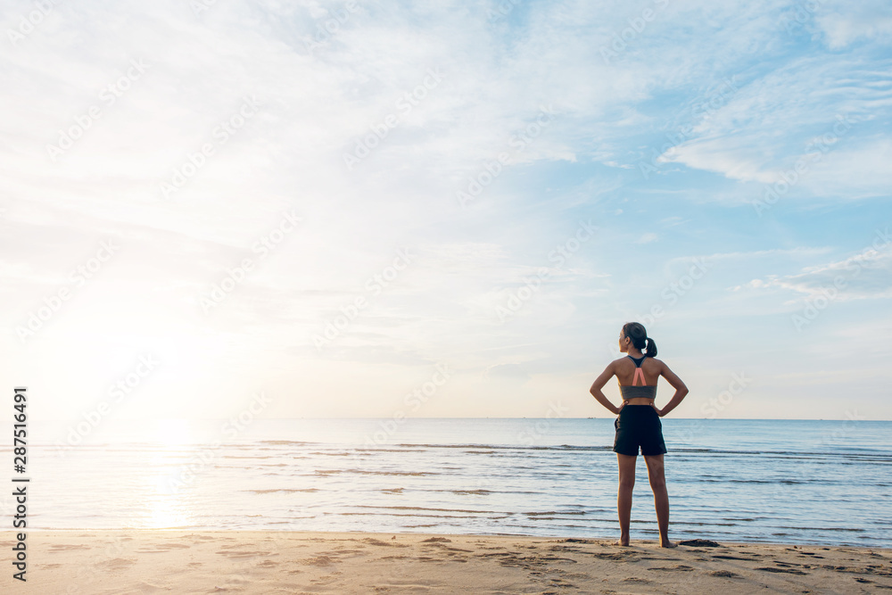 Silhouette of an athletic woman running on the beach during sunset time