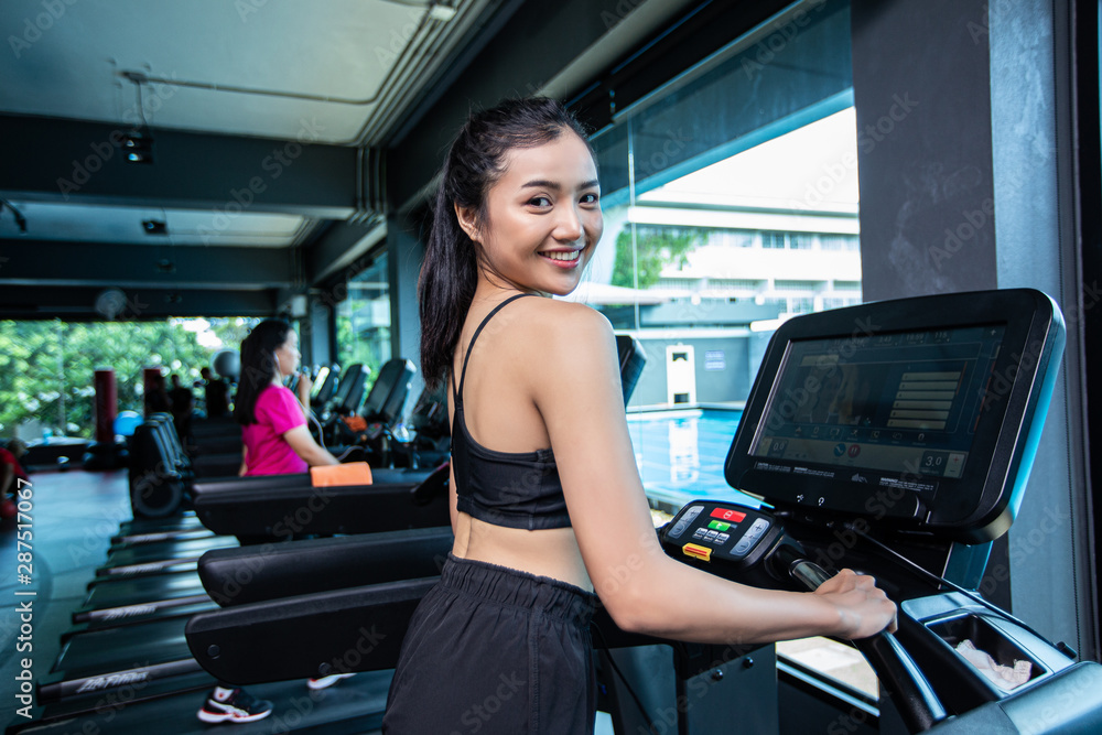 Beautiful fitness women prepare for running at the treadmill in the gym. Beautiful fitness women prepare for running at the treadmill in the gym.