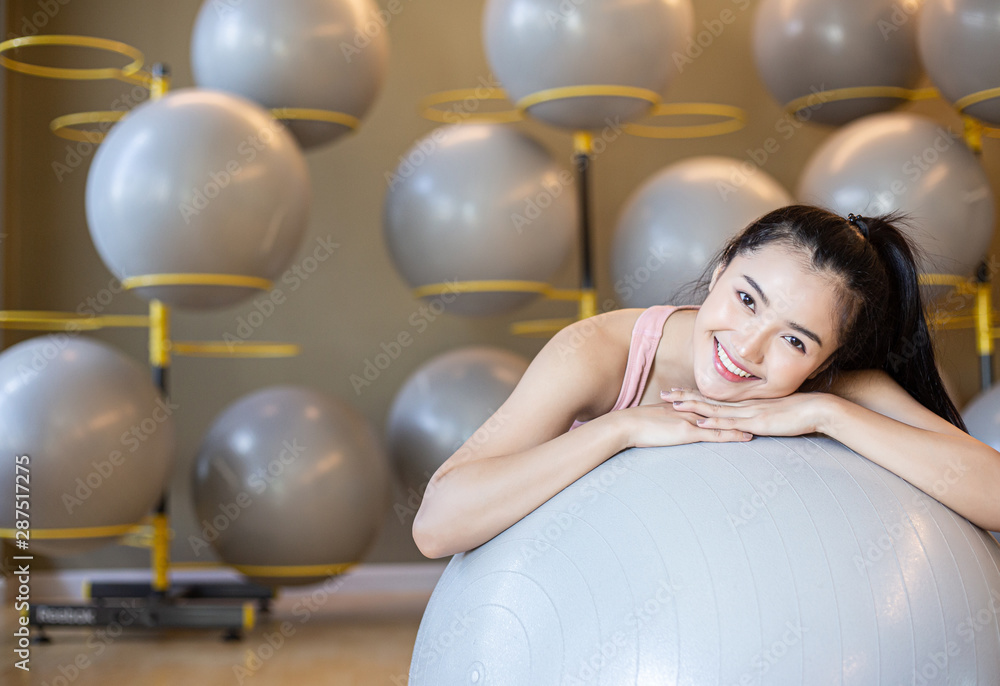 Naklejka premium The girl sitting relax with the ball in the gym.