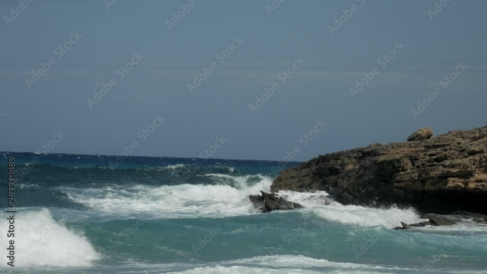 Powerful waves from the ocean crashing on rocks and stones on the coast. Wide Shot. Beautiful summer day in Mallorca, Spain. 4K