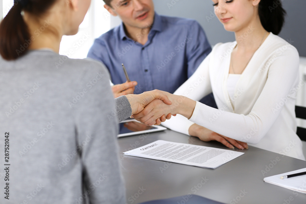 Group of business people shaking hands after discussing questions at meeting in modern office. Handshake close-up. Teamwork, partnership and agreement in business concept Group of business people shaking hands after discussing questions at meeting in modern office. Handshake close-up. Teamwork, partnership and agreement in business concept