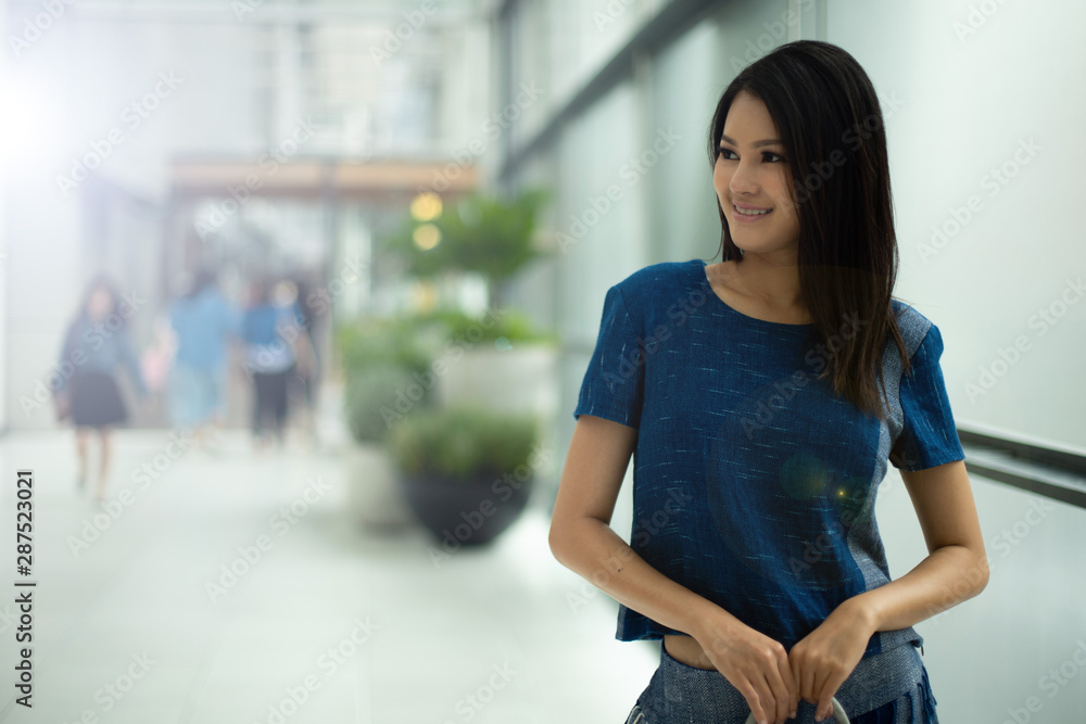 Asian Beautiful Woman in Indigo Blue local cotton dress present new collection on ready to wear clothes in fashion store which has big windows and blur background for copy space text logo