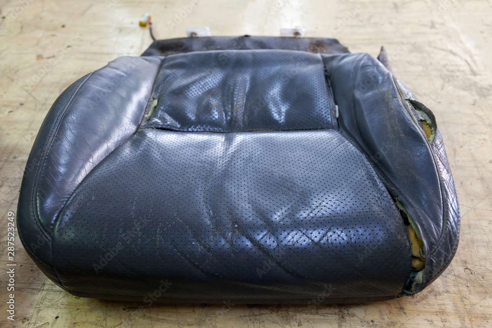 An old car seat made from tattered and torn leather upholstery on a