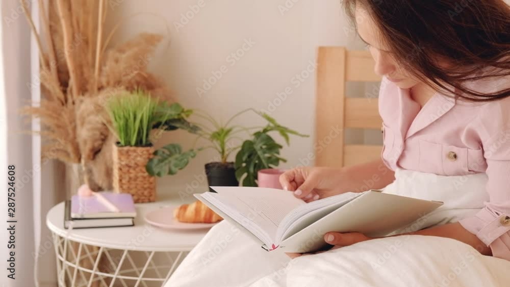 Morning leisure. Relaxation rest hobby. Girl enjoying reading favorite book eating croissant. Morning leisure. Relaxation rest hobby. Girl enjoying reading favorite book eating croissant.