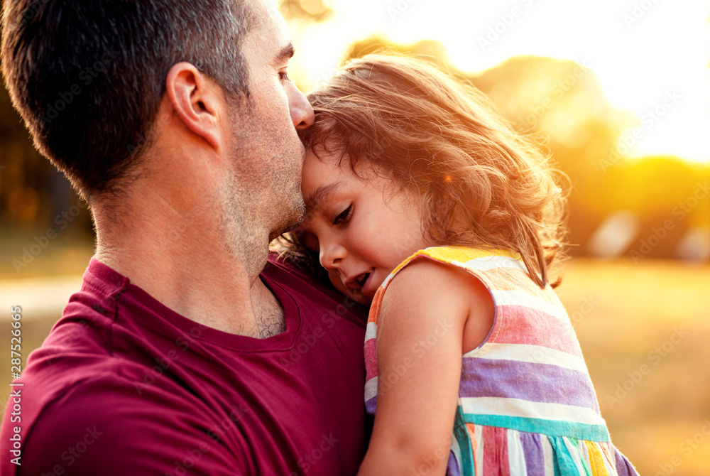 Portrait of father holding daughter in his hands and hugging each other outdoors.