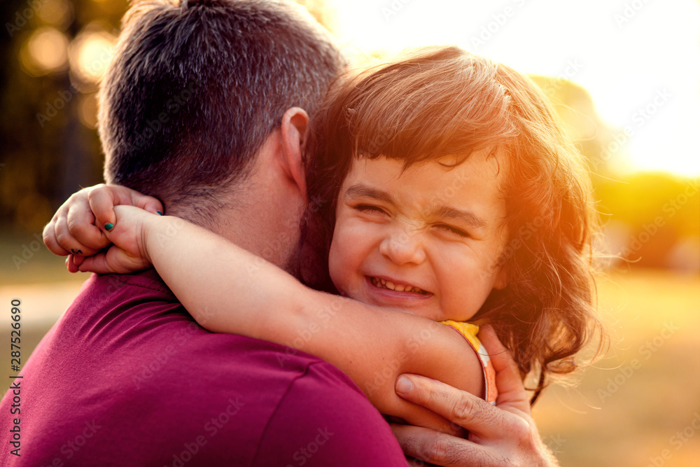 Portrait of father holding daughter in his hands and hugging each other outdoors. Portrait of father holding daughter in his hands and hugging each other outdoors.
