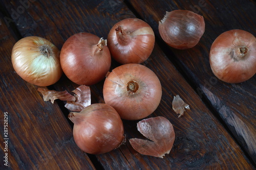 Several ripe onions isolated on a dark wooden background. Concept vitamins  healthy food