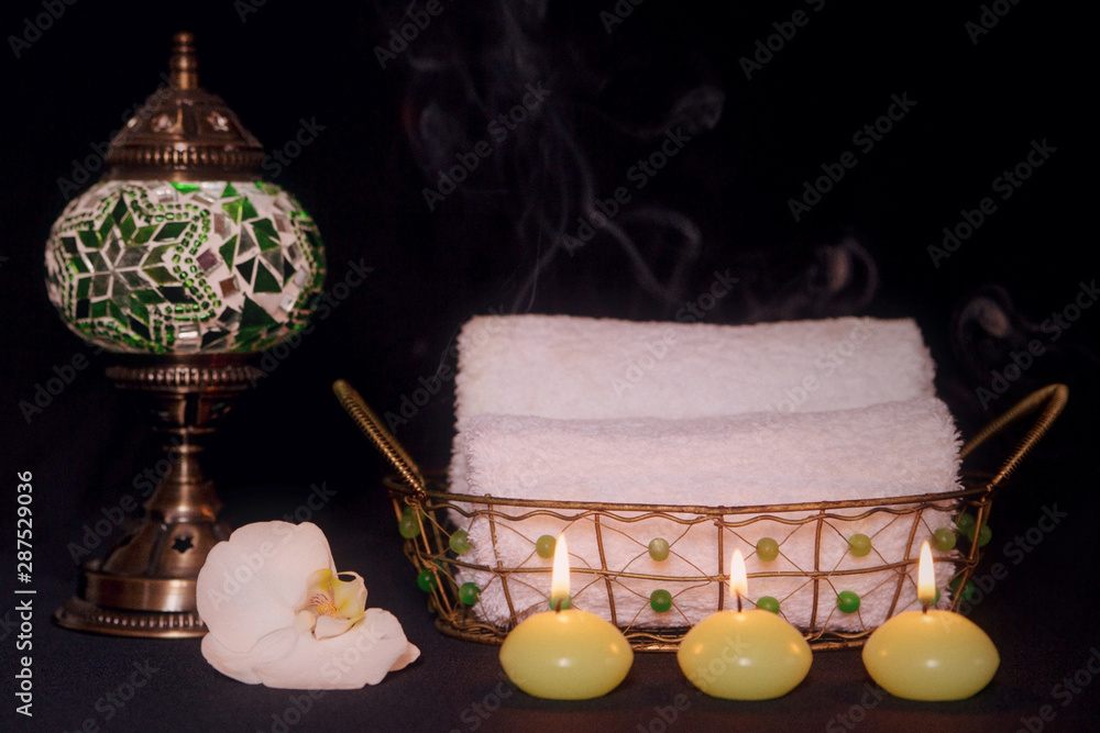 Escena relajante con velas, toallas para masaje, una lámpara árabe y una  orquídea blanca sobre fondo negro. Stock Photo | Adobe Stock