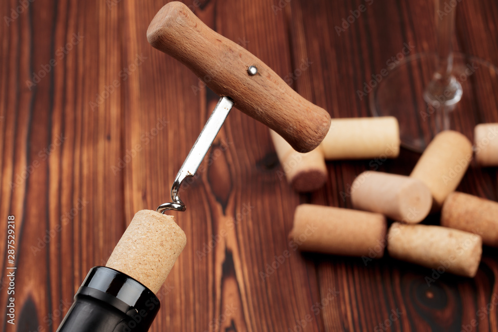 Bottle of wine and cork and corkscrew on wooden table - image