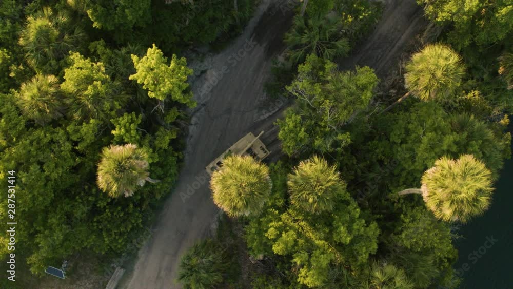 Drone Shot of tank driving in daylight. Birds Eye view of strategic military movement through forrest.