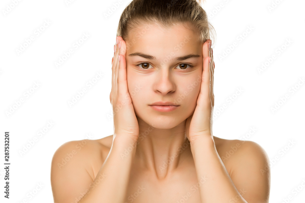Young woman tightening her face skin with her hands on white background Young woman tightening her face skin with her hands on white background