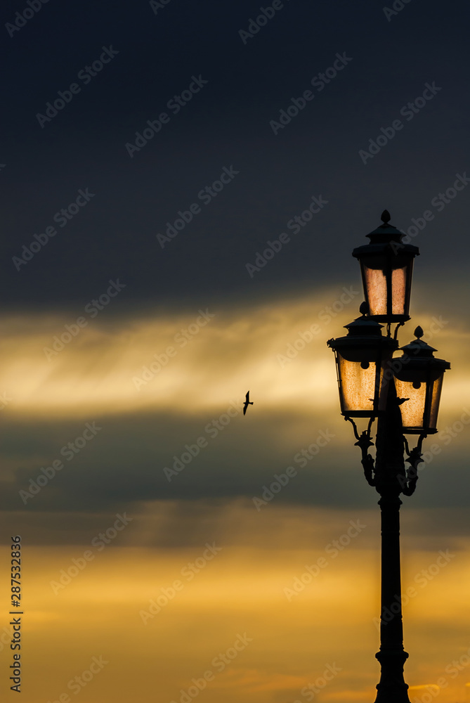 Old traditional Venice street lamp at sunset in a romantic and unique atmosphere (with copy space)