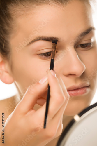 closeup of woman shaping her eyebrows with brush