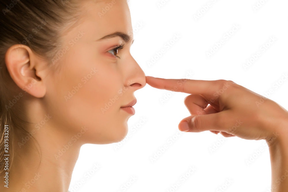 profile of young woman touches her nose on white background profile of young woman touches her nose on white background