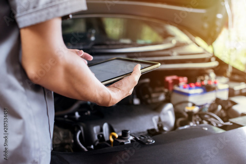 The mechanic uses a tablet to check the engine.