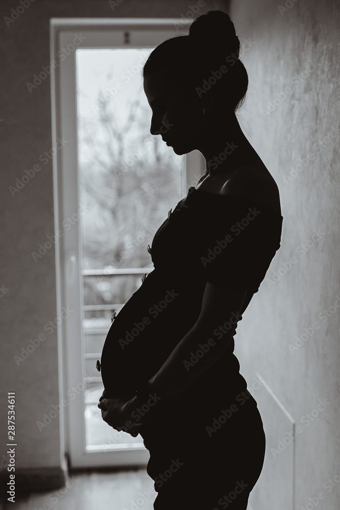 Pregnant woman touching her tummy. Black and white photo.