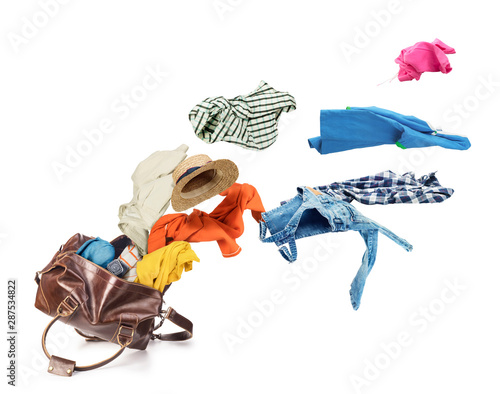 Clothes flying from brown skin luggage bag isolated on a white background photo