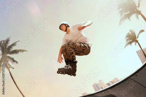 Obraz na płótnie Rollerskater man is performing tricks in skatepark on sunset.
