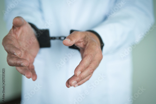 Doctor's hands are handcuffed. Violation of medical law and corruption