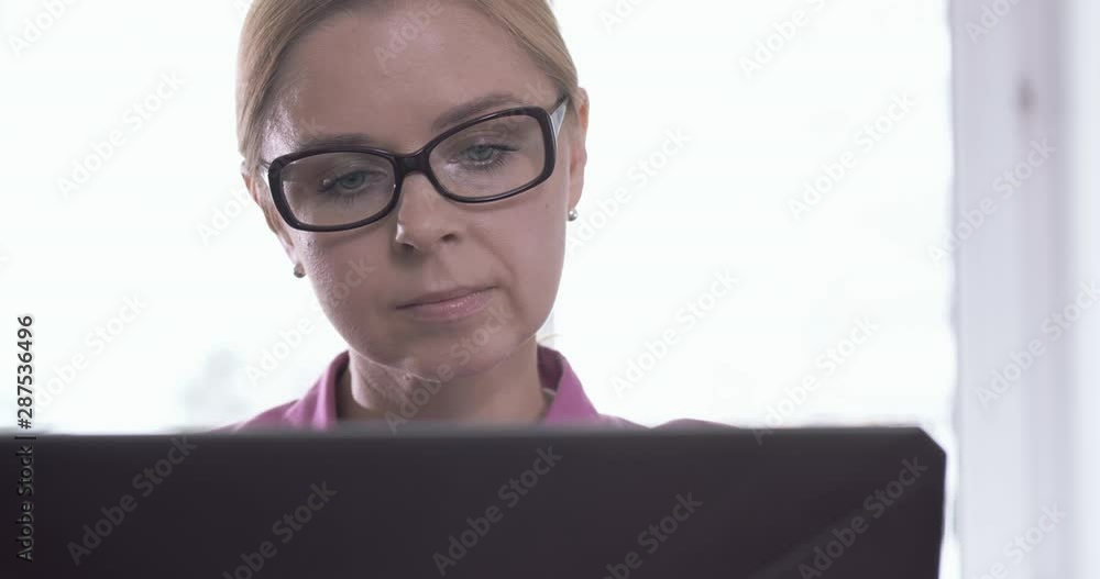 Portrait of smiling woman wearing glasses working at home with a laptop Portrait of smiling woman wearing glasses working at home with a laptop