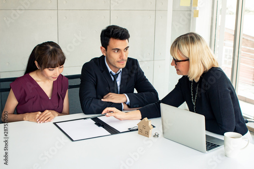 Husband and wife consult with the owner on the contract of house sale.