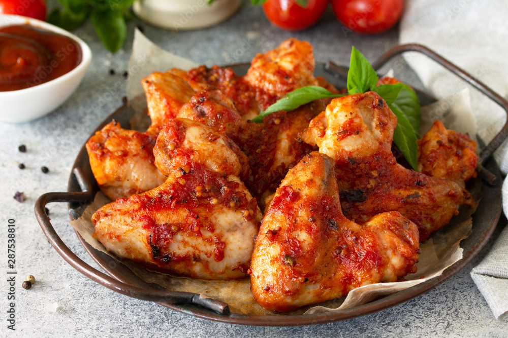 Tasty snack close-up. Baked chicken wings with mustard tomato sauce on a concrete table. Tasty snack close-up. Baked chicken wings with mustard tomato sauce on a concrete table.