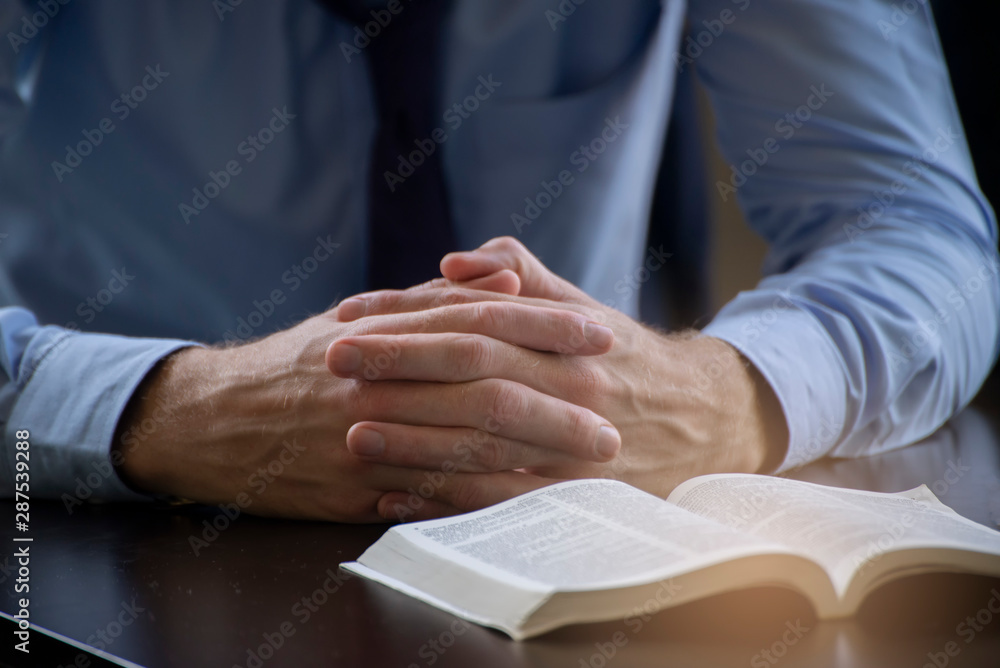 Obraz premium Pray and bible concept.Hand in hand together on bible by man (worship christian),thinking and closed her eyes at bed room.Person front view,Asian male praying,hope for peace, horizontal banner.