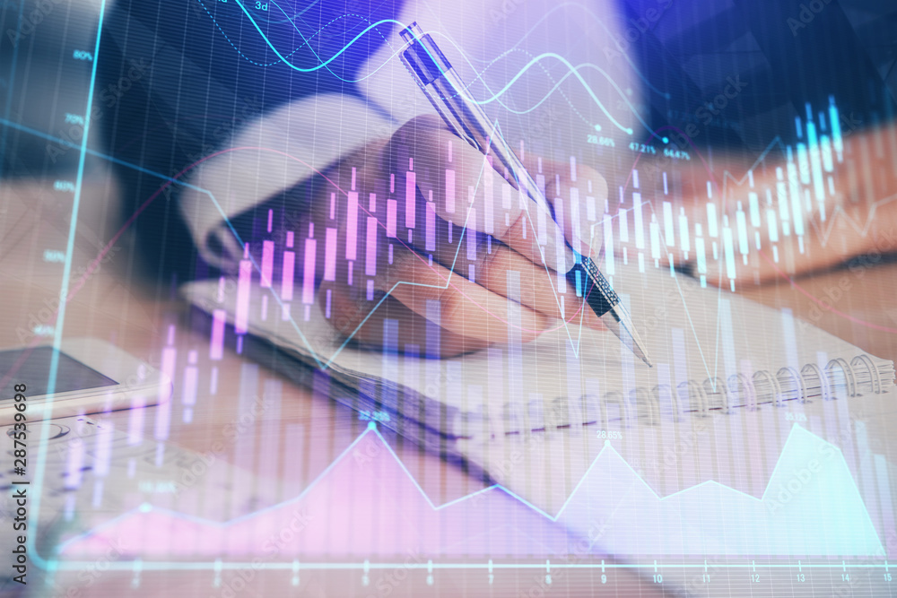 A woman hands writing information about stock market in notepad. Forex chart holograms in front. Concept of research. Multi exposure A woman hands writing information about stock market in notepad. Forex chart holograms in front. Concept of research. Multi exposure