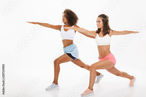Portrait of two beautiful multinational women in sportswear doing fitness exercises