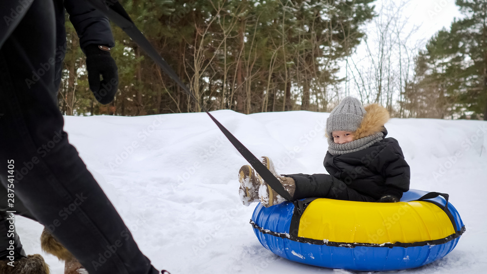 custom made wallpaper toronto digitalHappy kid boy in tubing is smiling and looking at camera. Young parents are running and sliding their son in tubing in winter park.
