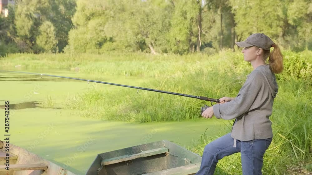 female fishman catches fish on river. Woman fisherman throws fishing rod into water of river. female fishman catches fish on river. Woman fisherman throws fishing rod into water of river.