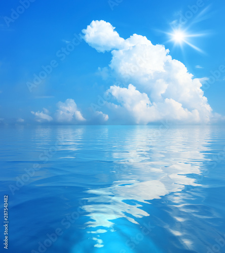 blue sky with white clouds and sun over the sea