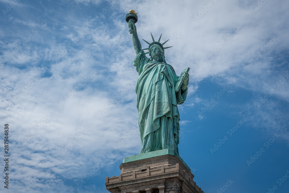 Shot of the Statue of Liberty in New York City, Usa. The shot is taken during a beautiful sunny day with a blue sky and white clouds in the background	